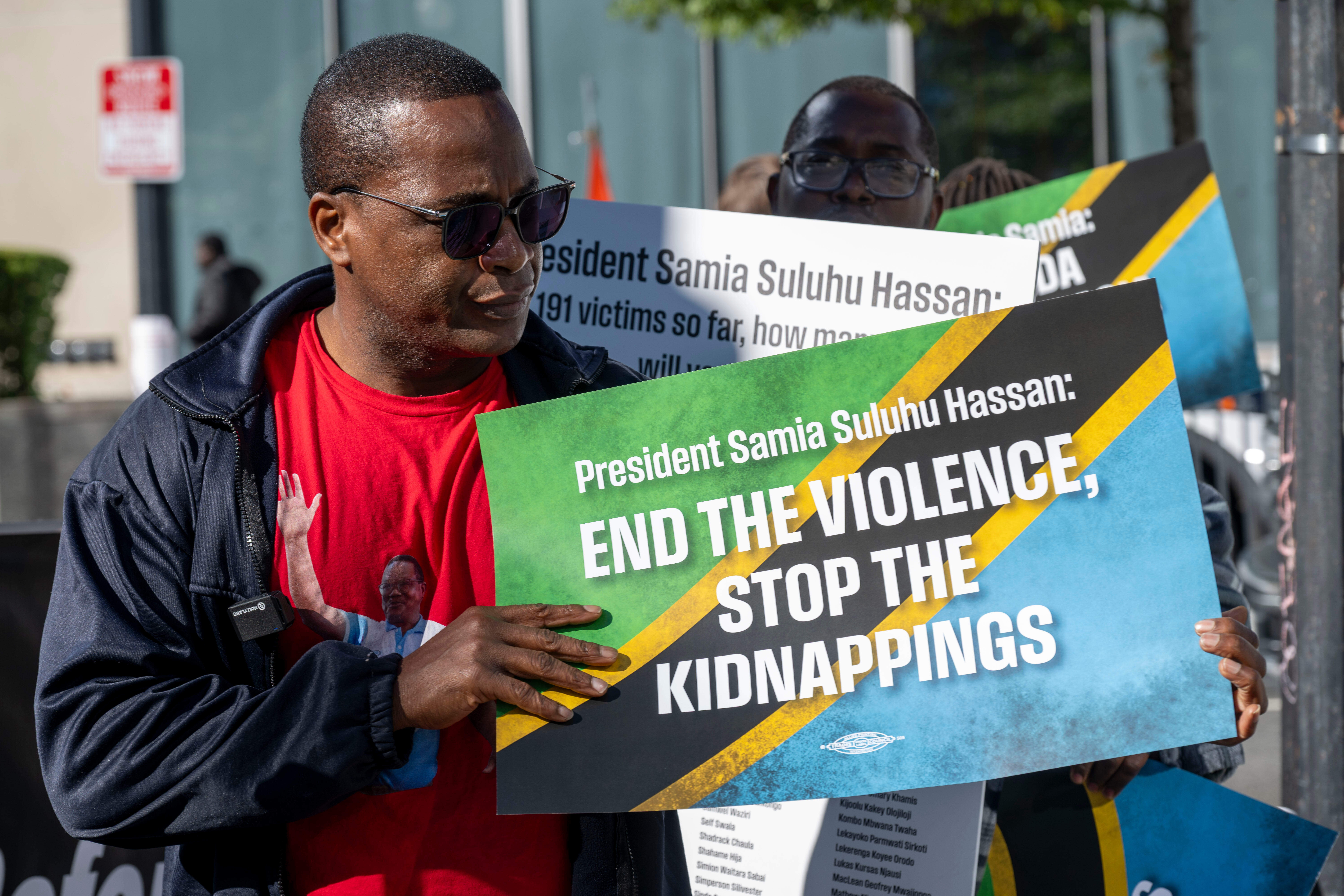 A man holds a sign reading "President Samia Suluhu Hassan: END THE VIOLENCE, STOP THE KIDNAPPINGS" at a March for Justice in Tanzania.