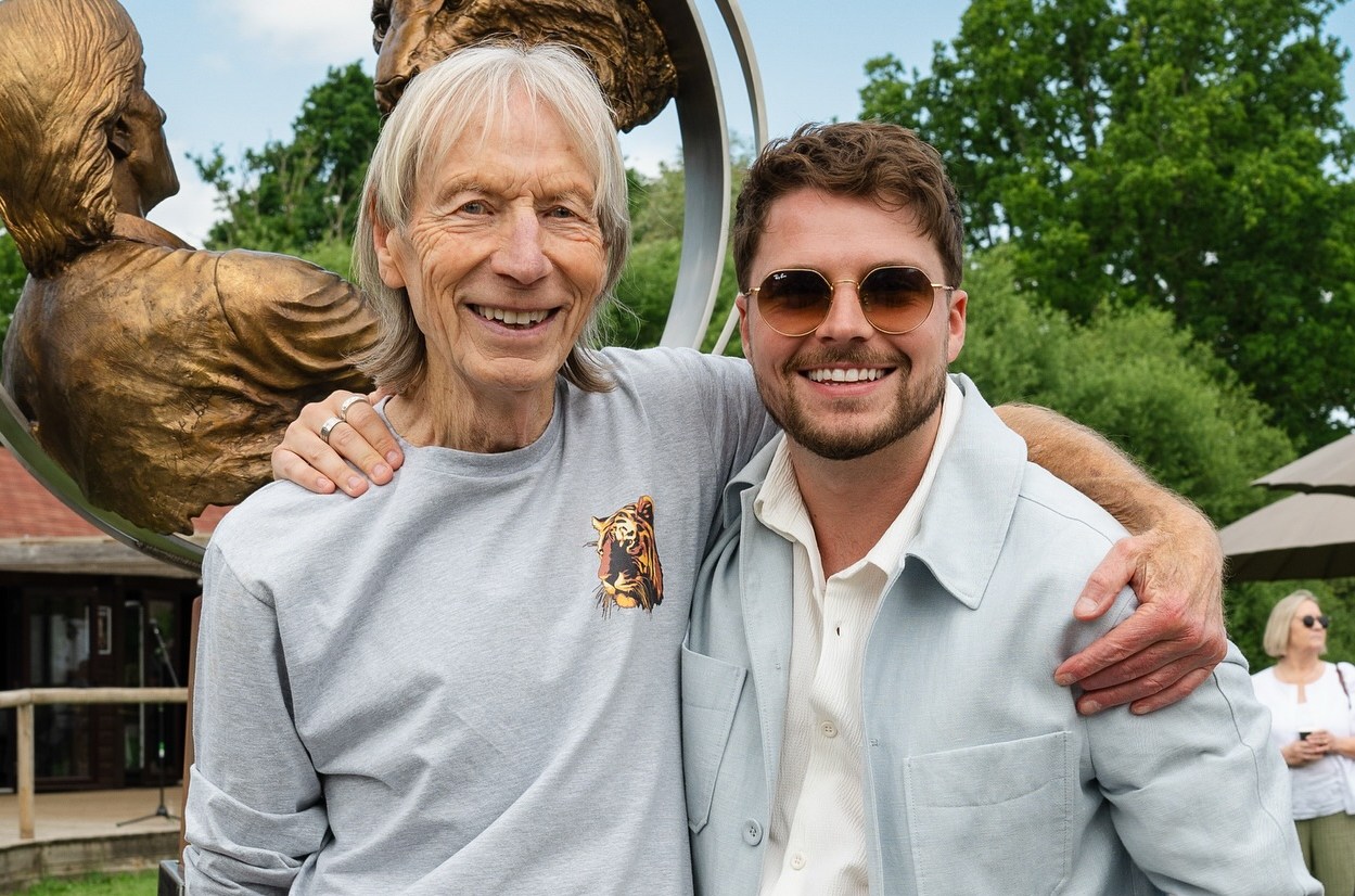 Cam Whitnall and Peter Sampson smiling in front of a bronze sculpture.