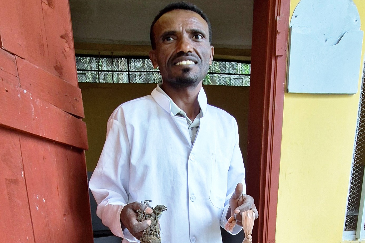 A veterinarian holding a large quantity of foreign objects removed from a donkey, with a box of more foreign objects.