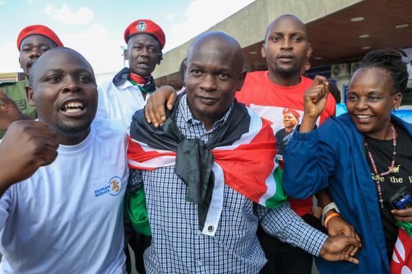 Kenyan human rights activist Nicholas Oyoo, centre, arrives at Jomo Kenyatta International Airport (JKIA) in Nairobi, Kenya, Saturday, Nov. 9, 2025. (AP Photo/Andrew Kasuku)