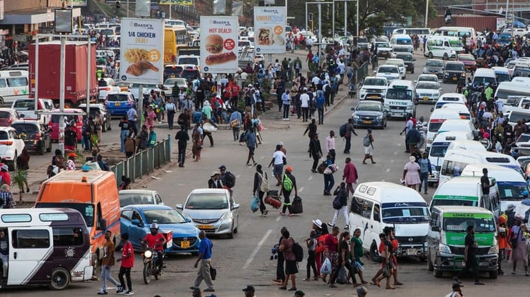 An overview of commuters at a minibus taxi area during...