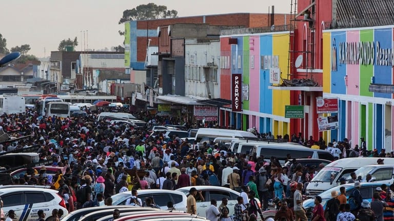 Commuters walk through parked vehicles during rush hour in downtown...