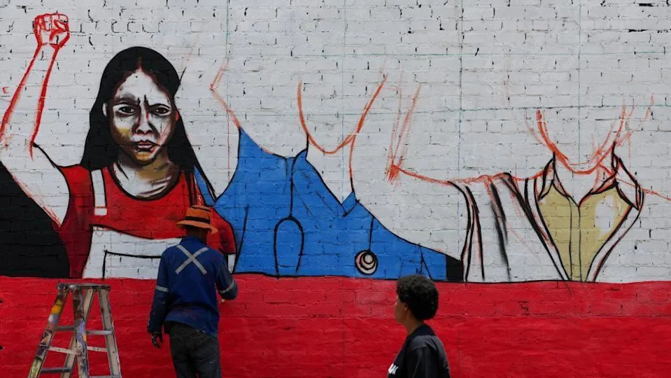 A person works on a mural with a message against gender-based violence in Johannesburg, South Africa, on 21 November 2025