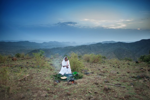 A woman performs a traditional coffee ceremony on a hillside at sunrise outside Lalibela, Ethiopia.