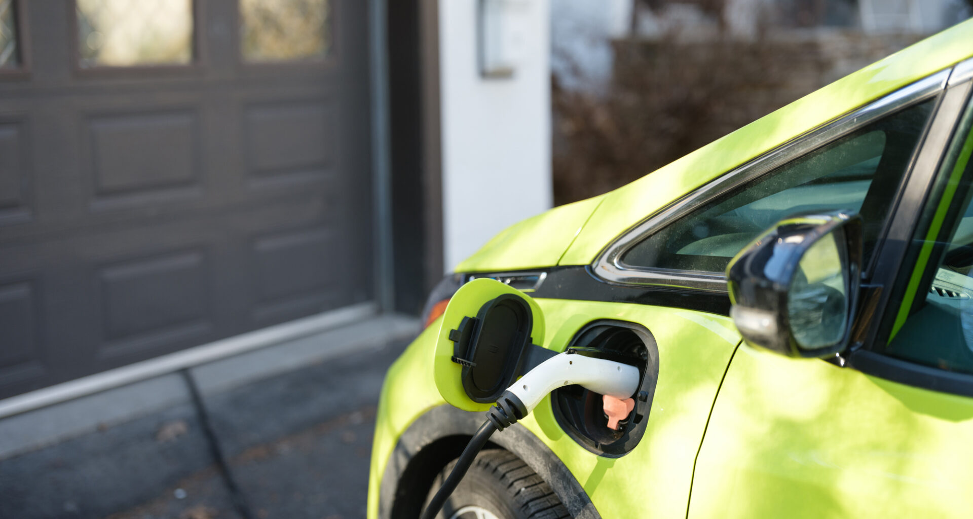 Electric car charging near garage in suburbs