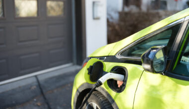 Electric car charging near garage in suburbs