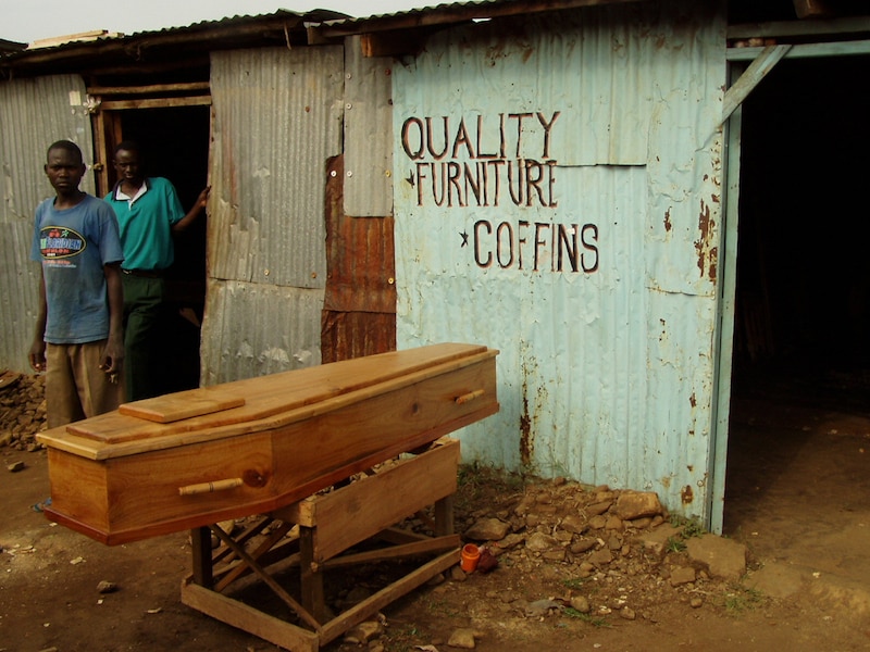 Two people stand outside a shop selling coffins.