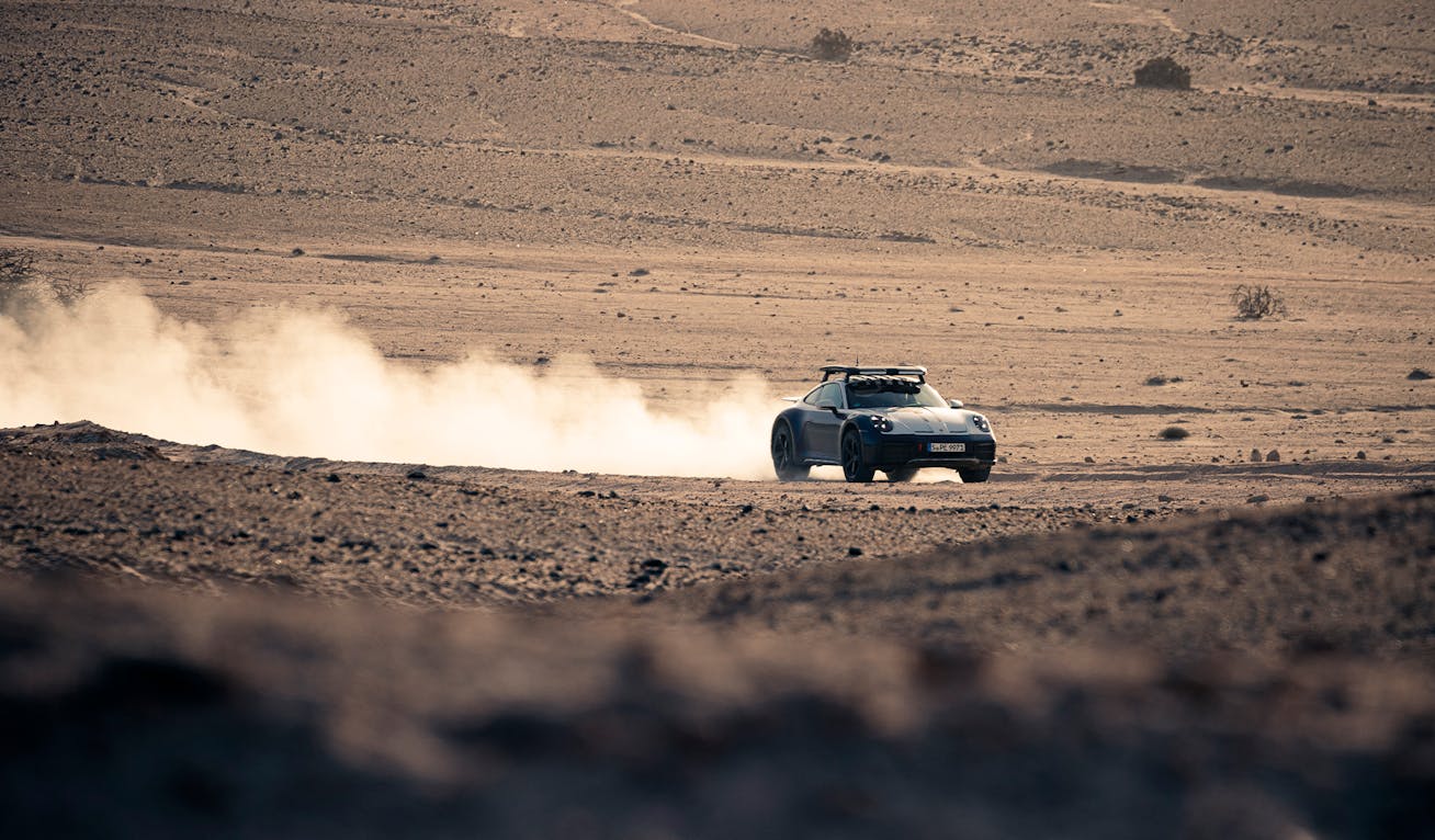Porsche 911 Dakar kicking up dust on Namibian desert road