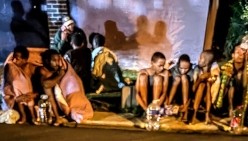 Suspected human trafficking victims sit on a pavement in Mulbarton in the south of Johannesburg on Monday night before being assisted by police and private security. (Photo: Aneesa Adams)