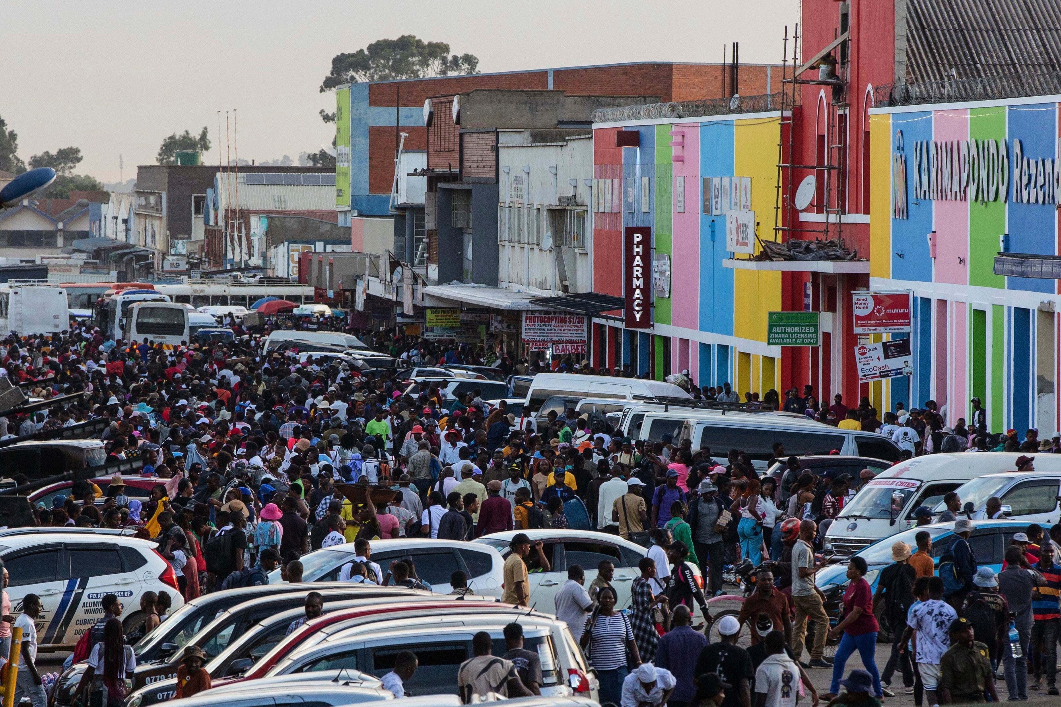 Commuters walk through parked vehicles during rush hour in downtown Harare, Zimbabwe, Tuesday, Dec. 16, 2025. (AP Photo/Aaron Ufumeli)