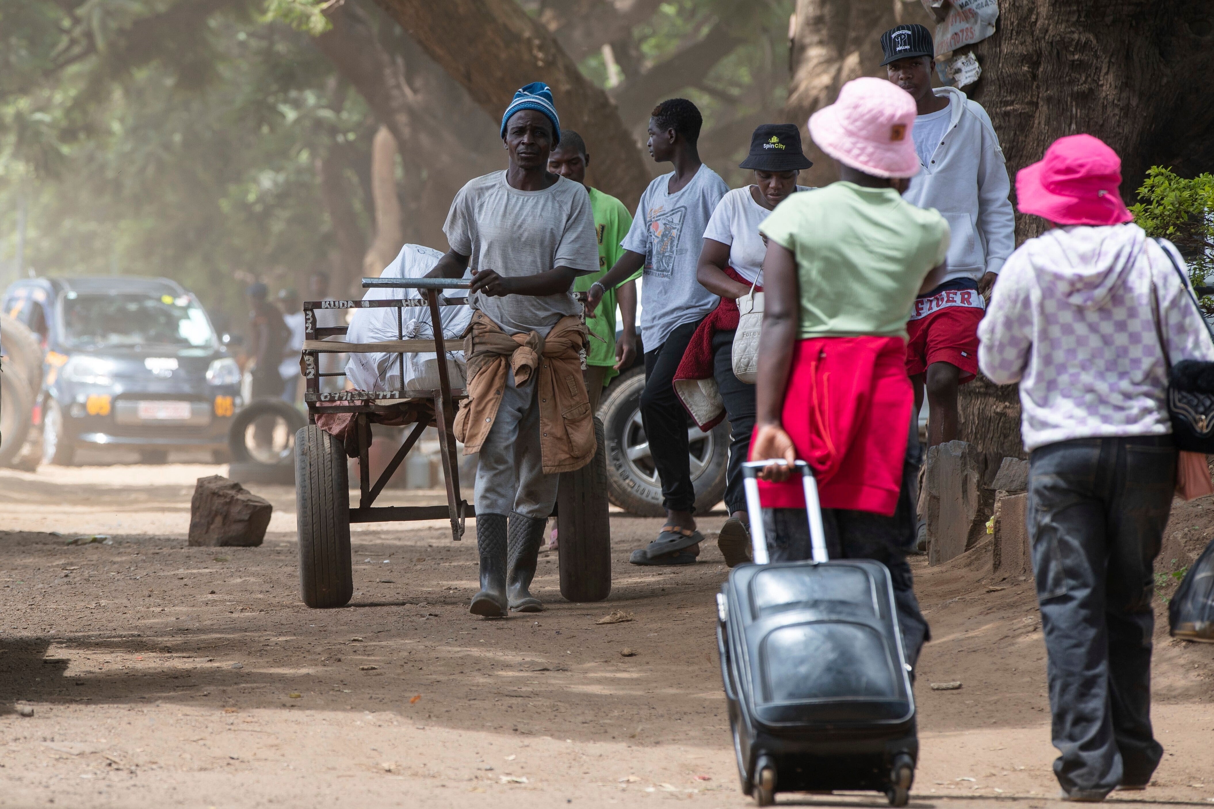 People walk on the sidewalk on the outskirts of Harare, Zimbabwe, Tuesday, Dec. 16, 2025. (AP Photo/Aaron Ufumeli)