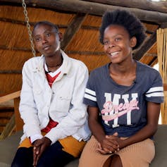 Two young women, seated and smiling
