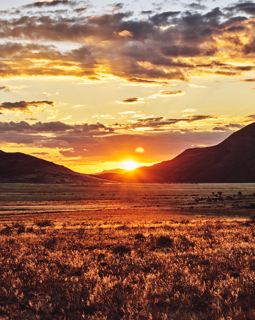 sunset over a mountainous landscape with grassy fields
