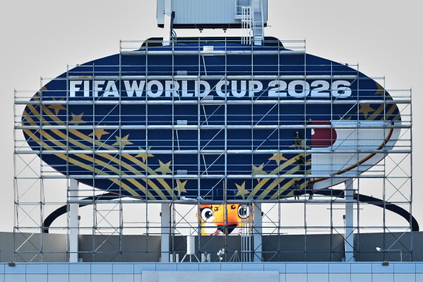 Workers cover a Kansas City Chiefs sign to FIFA World Cup 2026 as work continues to transform Arrowhead Stadium to Kansas City Stadium ahead of the FIFA World Cup soccer tournament Monday, June 8, 2026, in Kansas City, Mo. (AP Photo/Charlie Riedel)