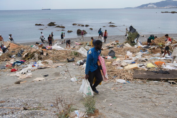 Migrants who crossed from Morocco into Spain gather their belongings after being cleared from the beach in the Spanish exclave of Ceuta, Thursday, Aug. 20, 2026. (AP Photo/Antonio Sempere)