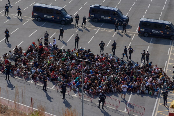Migrants who crossed from Morocco into Spain are escorted by Spanish police to temporary shelters after being cleared from a beach in the Spanish exclave of Ceuta on Thursday, Aug. 20, 2026. (AP Photo/Antonio Sempere)