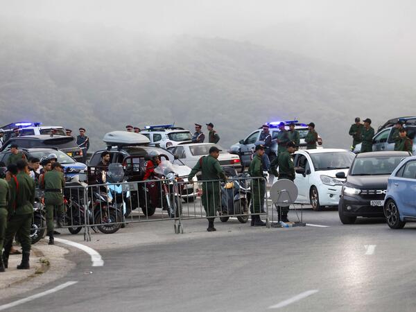 Police officers man a roadblock on the outskirts of Fnideq, on the Morocco-Spain border, on July 30, 2026. Hundreds of people were converging on Morocco's northern town of Fnideq on July 30 evening, following rumours that the border with Spain's Ceuta had opened, according to an AFP journalist. Spain had earlier reported nine deaths after hundreds of migrants entered the north African exclave from Morocco, mainly by swimming. (Photo by Abdel Majid BZIOUAT / AFP)