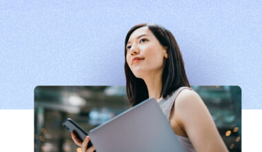 Person holding a laptop and smartphone, looking upward outdoors, with a softly blurred urban background and a blue textured graphic overlay above.