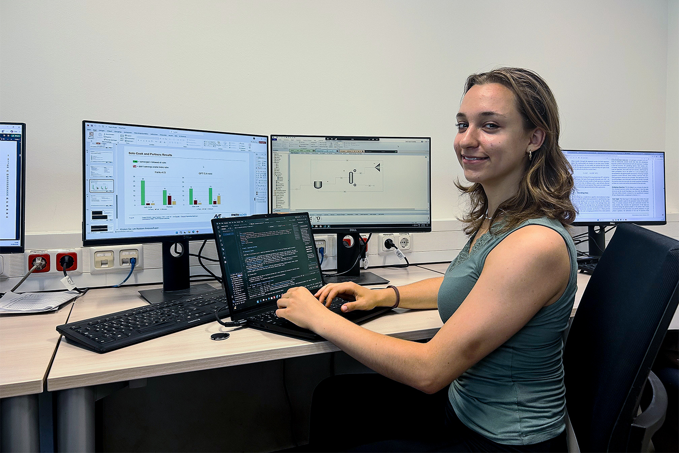Sierre Ternoey, a Northeastern industrial engineering student, working at a research desk in Aachen, Germany, coding on a laptop with data displays on multiple monitors.