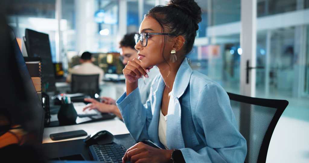 woman in office wearing business attire and looking intensely at computer screen