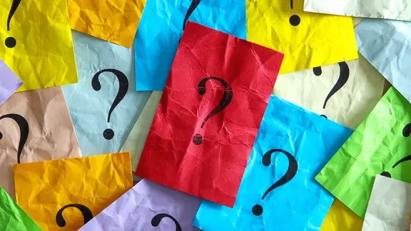 Mehrere bunte, zerknitterte Papierblätter liegen übereinander, jedes mit einem schwarzen Fragezeichen in der Mitte. Ein rotes Blatt mit Fragezeichen ist zentral und sticht hervor. | Fotolia/Stauke Mehrere bunte, zerknitterte Papierblätter liegen übereinander, jedes mit einem schwarzen Fragezeichen in der Mitte. Ein rotes Blatt mit Fragezeichen ist zentral und sticht hervor.