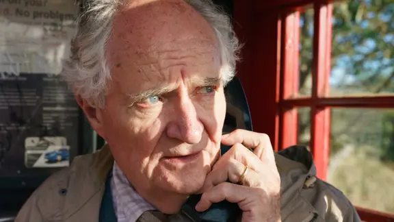 Gut 1.000 Kilometer legt Harold Fry (Jim Broadbent) auf seiner Reise zurück - in schlechtem Schuhwerk, wohlgemerkt. | Embankment Films/David Gennard Harold Fry (Jim Broadbent) steht in einer roten Telefonzelle und telefoniert.