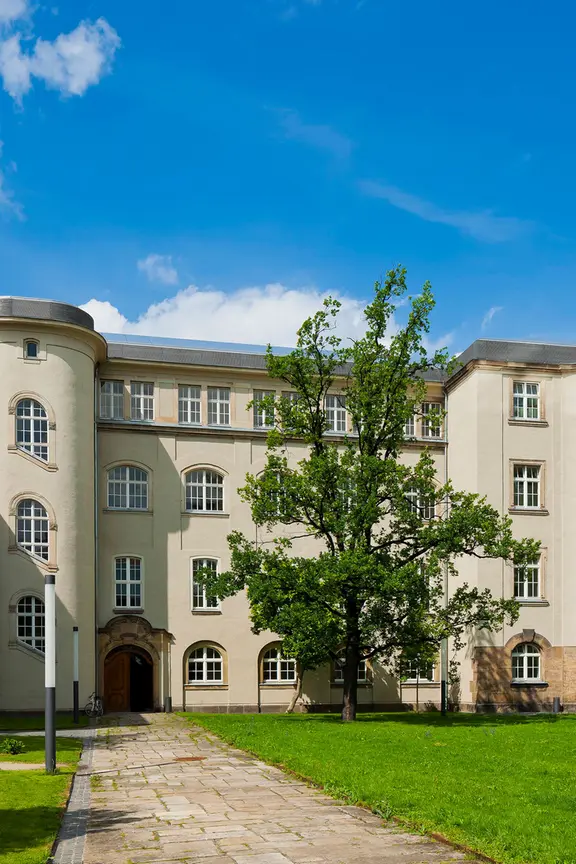 Die Hochschule für Bildende Künste in Dresden. Hier hat Gerhard Richter in den 50er-Jahren studiert. | imago images/Sylvio Dittrich Ein helles, viergeschossiges historisches Gebäude mit begrüntem Innenhof ragt in den blauen Himmel hinauf.