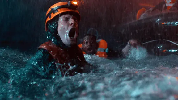 Szene aus dem Film "27.000 Leben": Zwei Menschen in Rettungswesten im stürmischen Wasser. | Netflix Szene aus dem Film "27.000 Leben": Zwei Menschen in Rettungswesten im stürmischen Wasser.