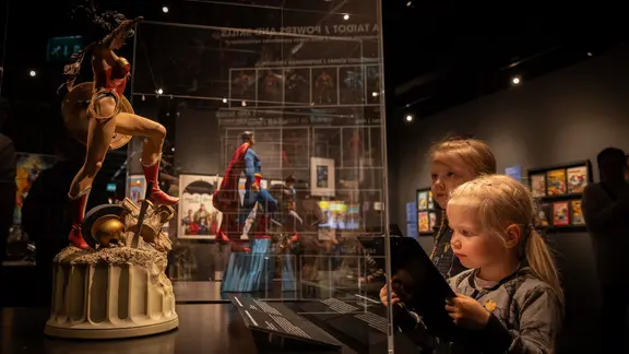 Eindrücke aus der Ausstellung "Mythos Superhelden": Zwei Mädchen betrachten eine Figur | Saarni Säilynoja/Museum Centre Eindrücke aus der Ausstellung "Mythos Superhelden": Zwei Mädchen betrachten eine Figur