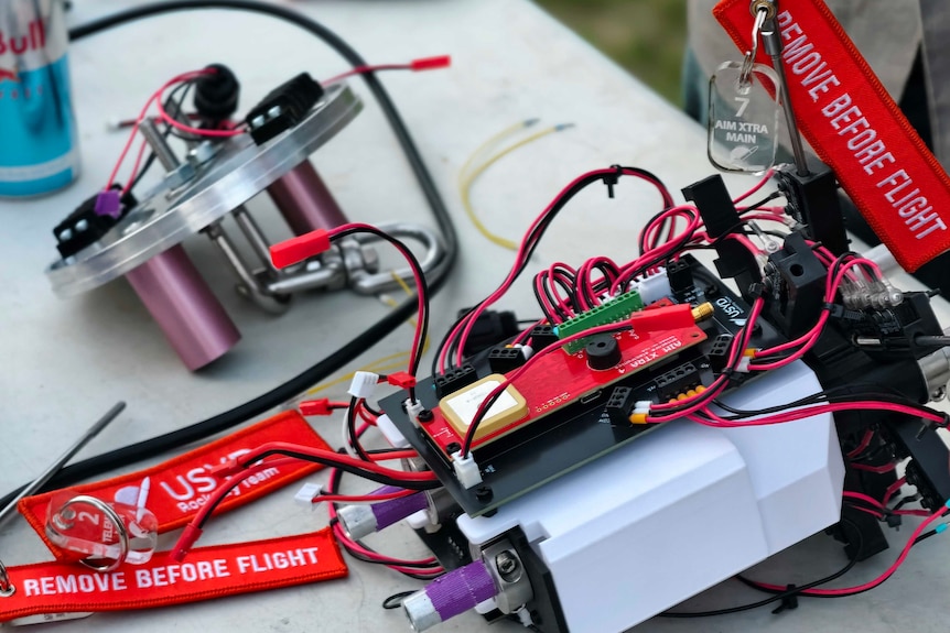 An assortment of wires connected to components of a miniature rocket