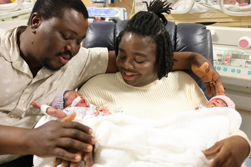 A man and woman cradling two newborns