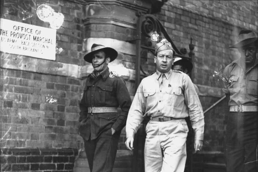 Black and white photo of two soldiers walking out of a building.