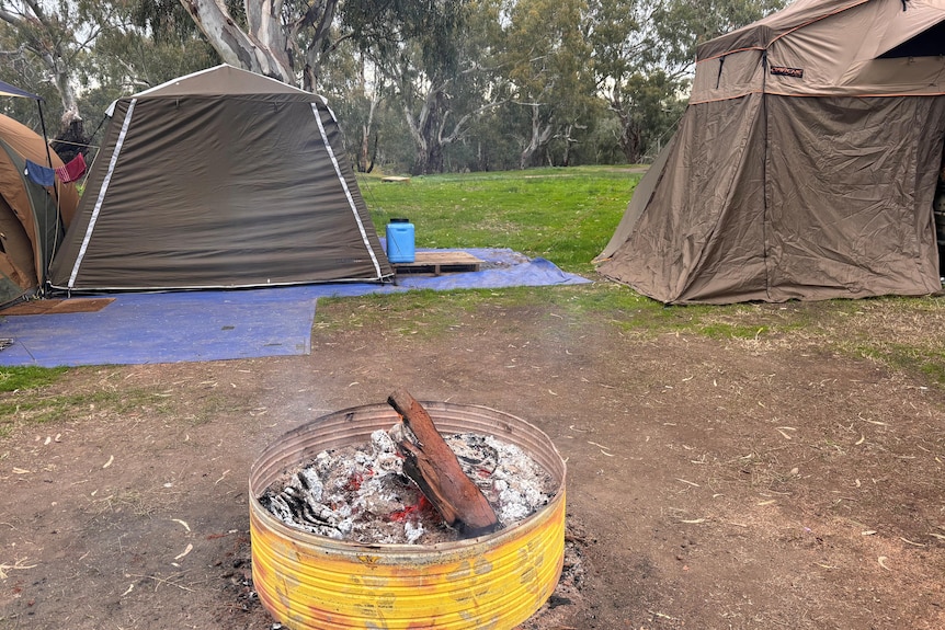 fire drum burning wood in the middle of several tents