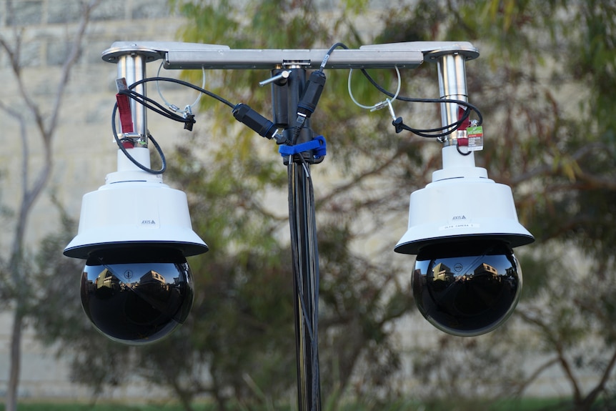 A close-up shot of two live facial recognition cameras on top of a pole.
