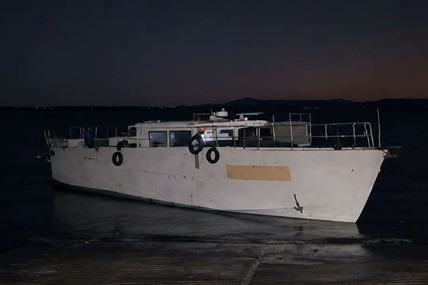 A large motor boat sits at the end of a boat ramp at night.