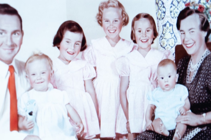 A historic photo of a family with two adults, three children and two babies
