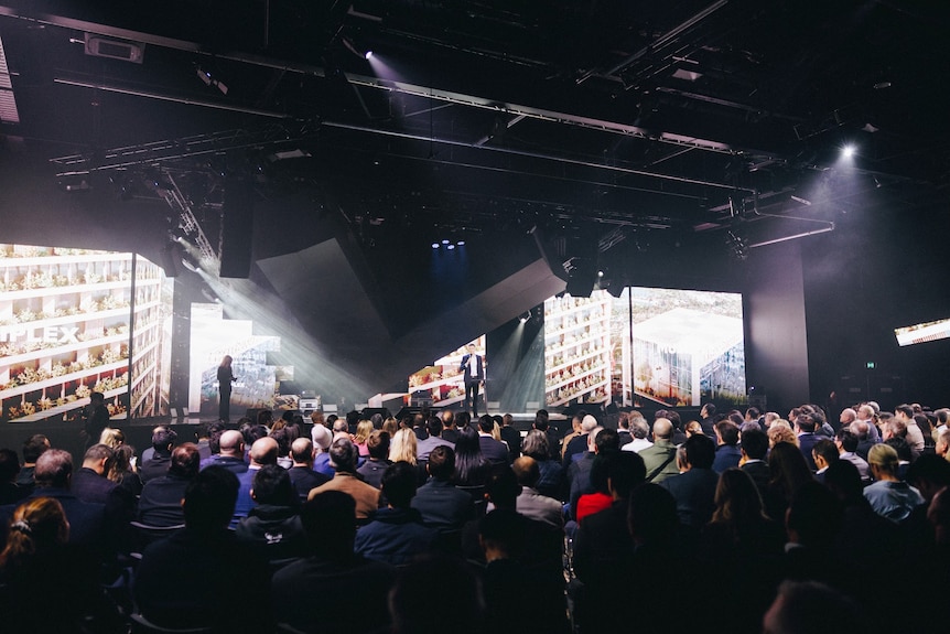 a large crowd of people seated in front of a stage.