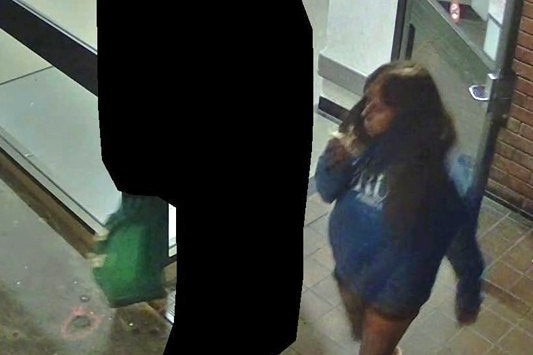 A woman and a person whose identity has been obscured outside a doorway.