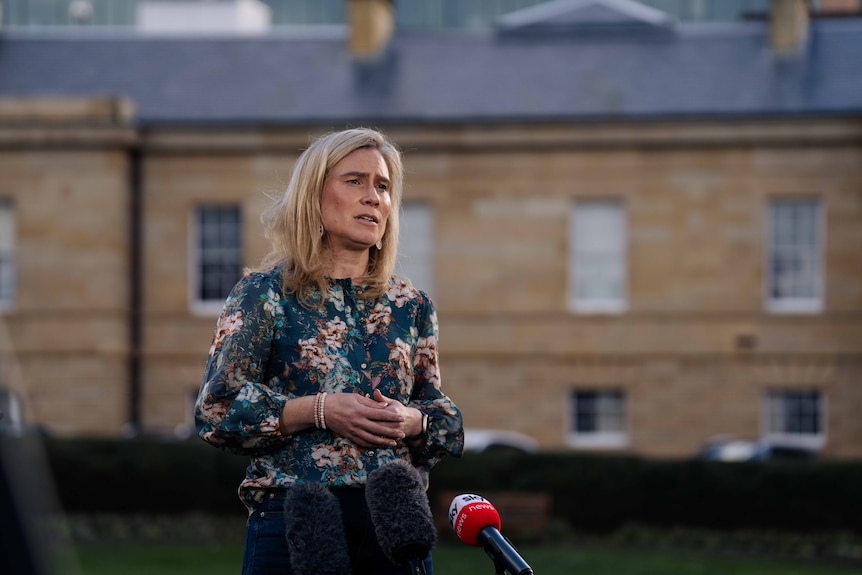 Woman with blonde hair speaks on a green lawn