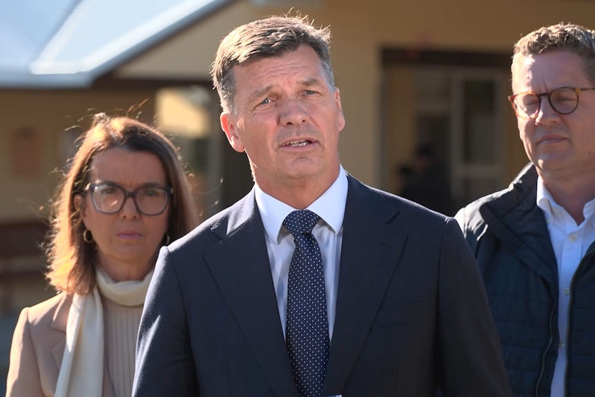 Angus Taylor facing a press conference wearing a suit