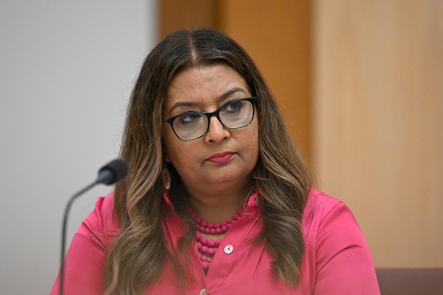 A woman sits in a room with a small microphone.