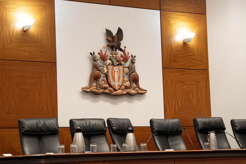 An empty court bench in front of the NT coat of arms
