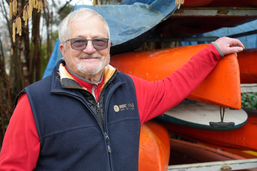 David Chitty standing in front of brightly coloured canoes.