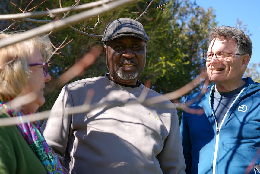 Group of three people smiling and talking to one another.