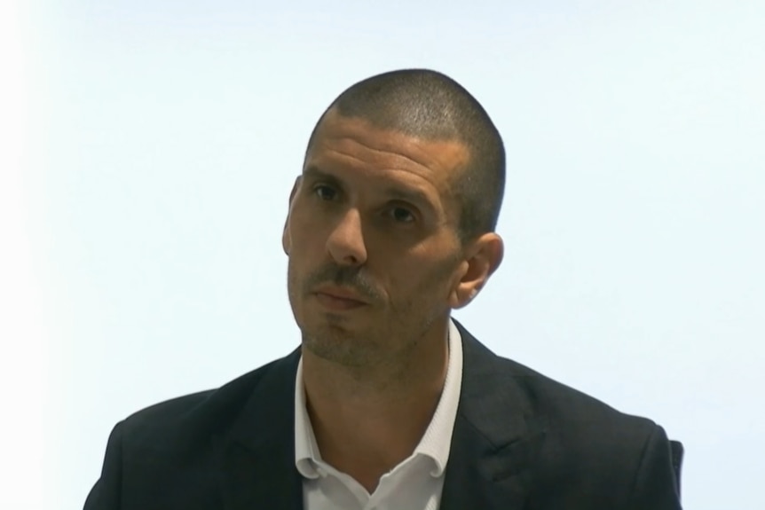 Dr Barracosa sitting at a desk speaking to counsel assisting.