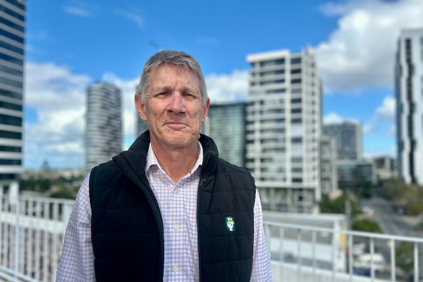 A portrait of a man with city buildings in the background.