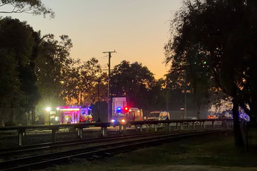 Sun rises and in the distance fire truck lights flash as crews battle house fire