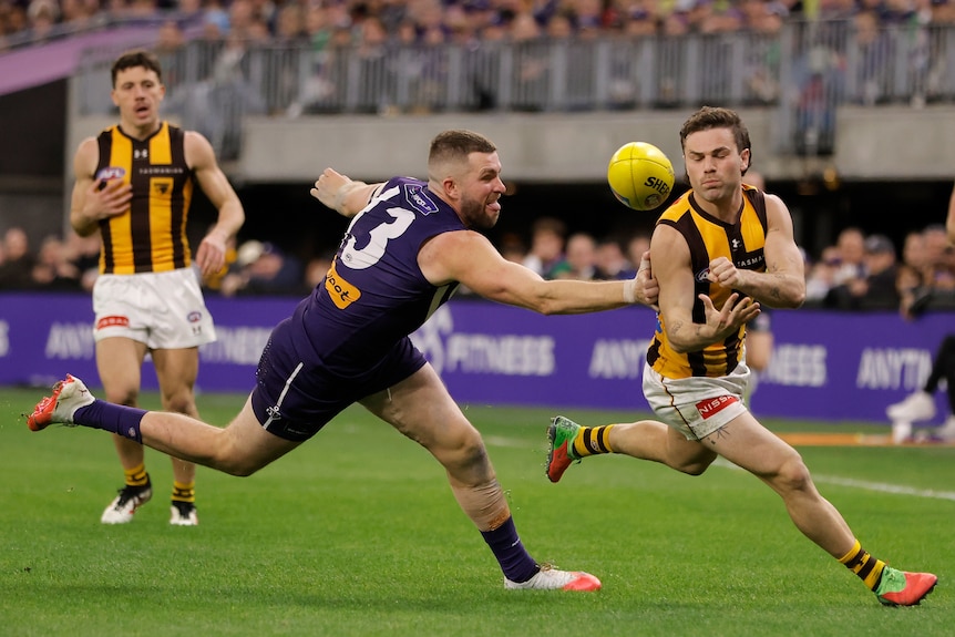 Nick Watson handballs past Luke Ryan in an AFL match.