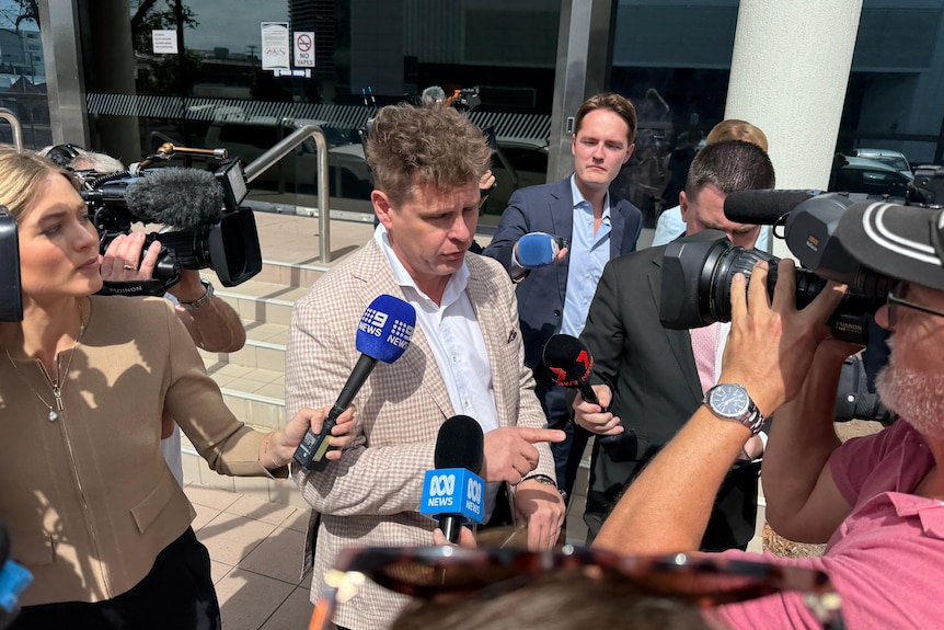 Lawyer in nude jacket with media microphones and cameras