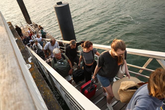 Des vacanciers de Lege-Cap-Ferret transportent leurs affaires le long de la jetée à leur arrivée à Arcachon, lors d’une opération d’évacuation de toute la presqu’île du Cap-Ferret, dans le sud-ouest de la France, le 24 juillet 2026.